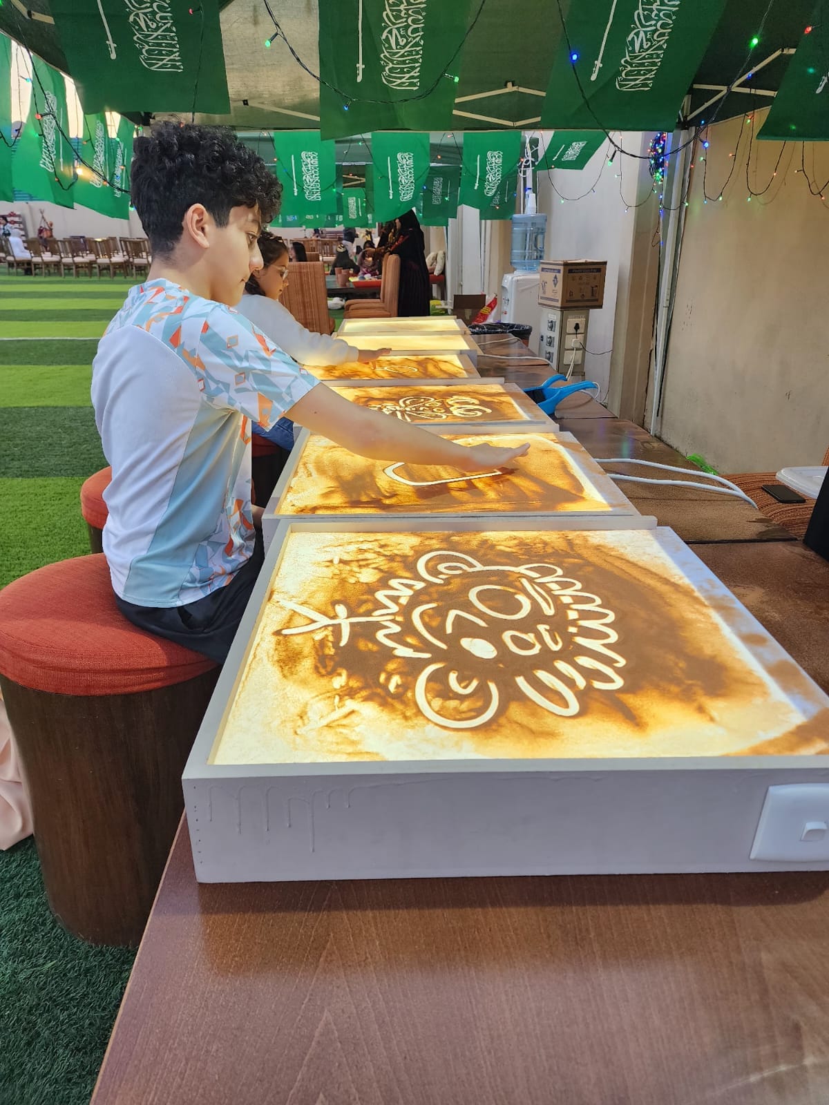 أطفال يرسمون الرمل في محطات النشاط المضيئة