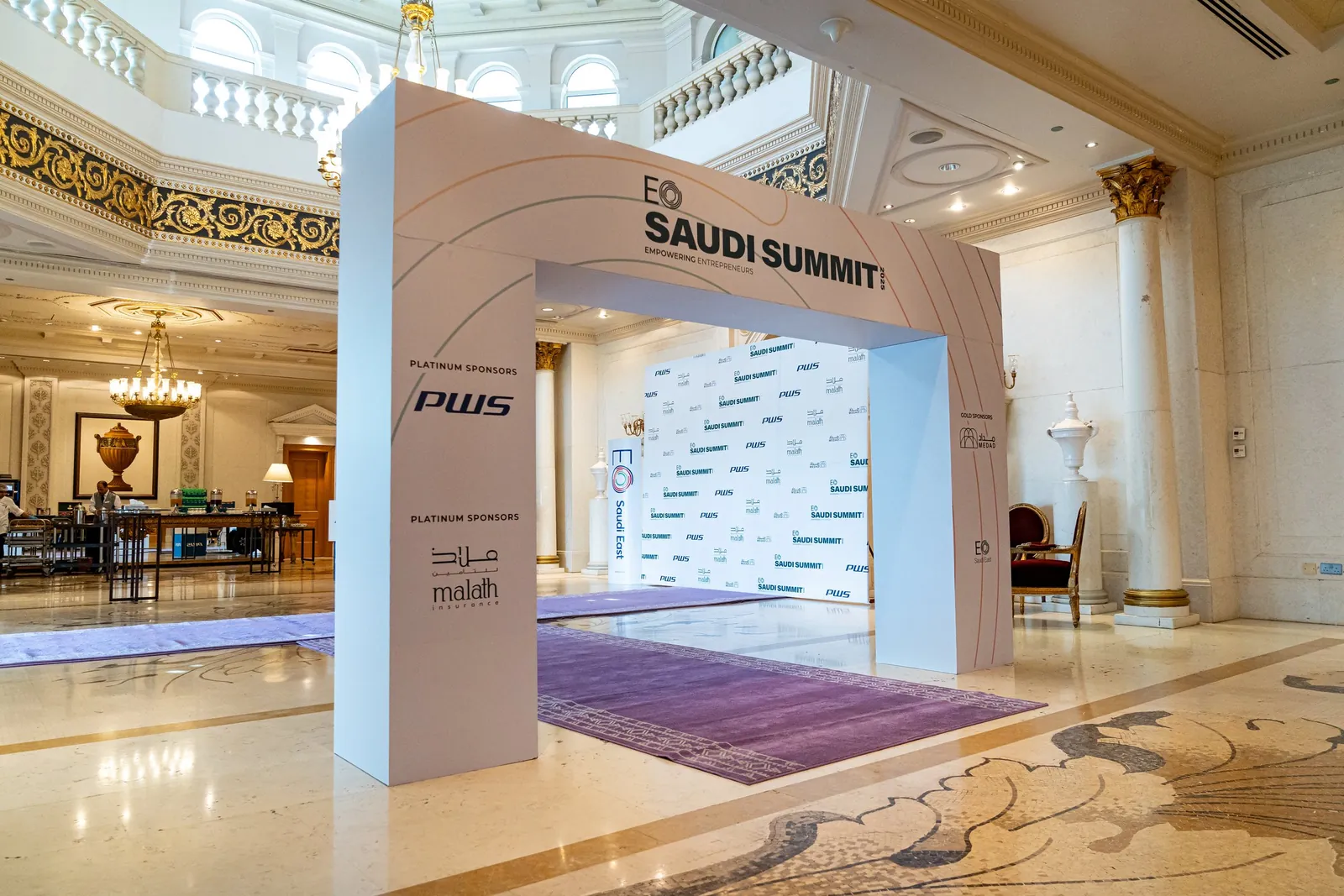 Branded entrance arch with sponsor panels and photo wall behind