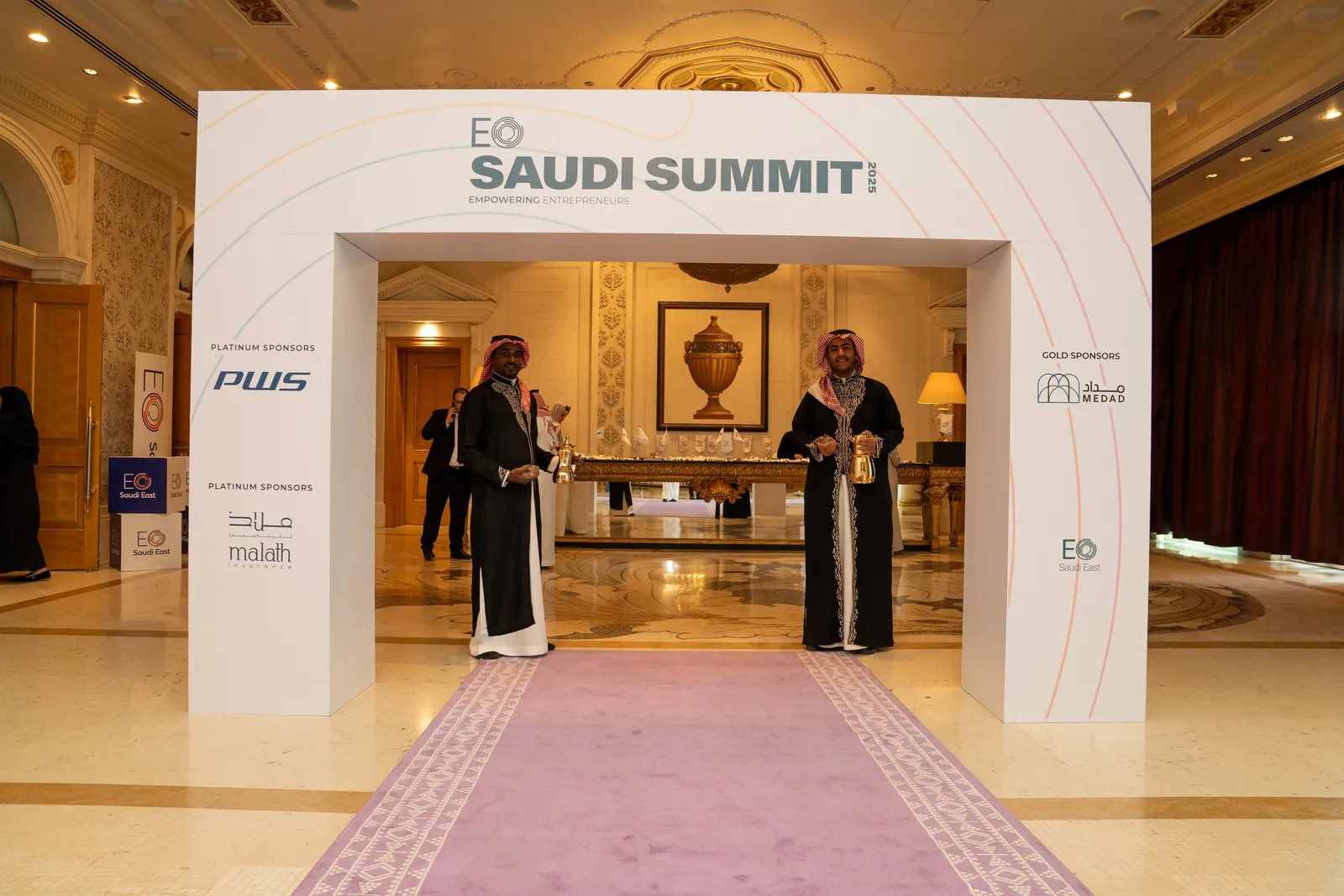 Hosts with dallah welcoming at EO Saudi Summit arch