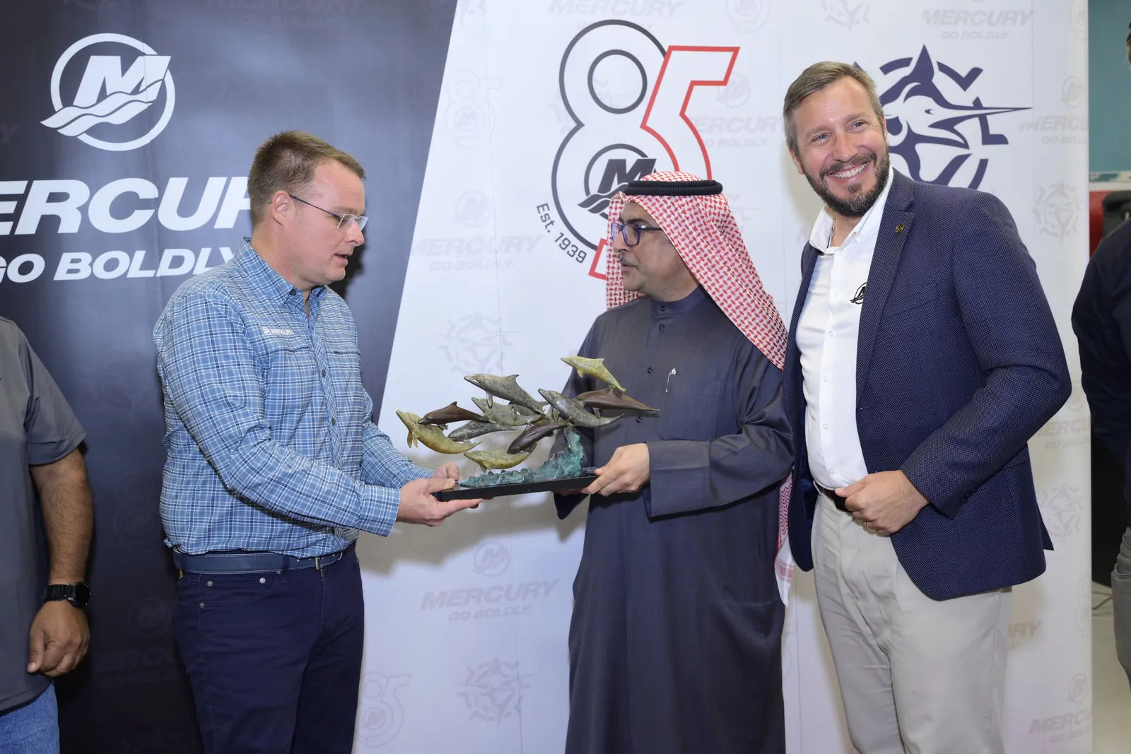 Smiling executives exchange dolphin sculpture gift