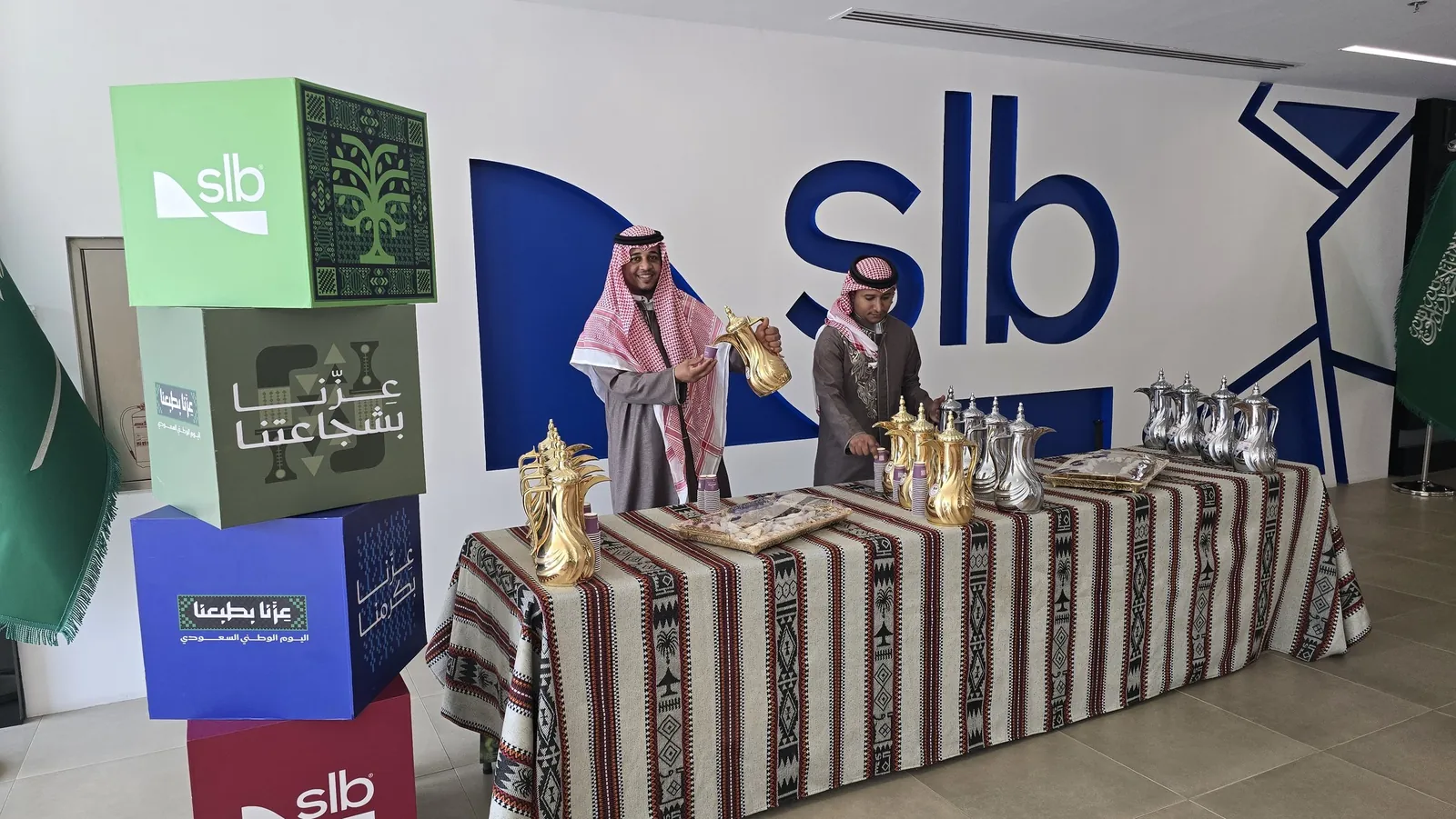 Coffee host pouring from a golden dallah at a Sadu-draped table