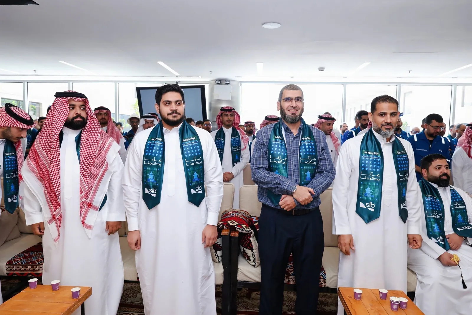 SLB staff in campaign scarves standing in the majlis, crowd behind