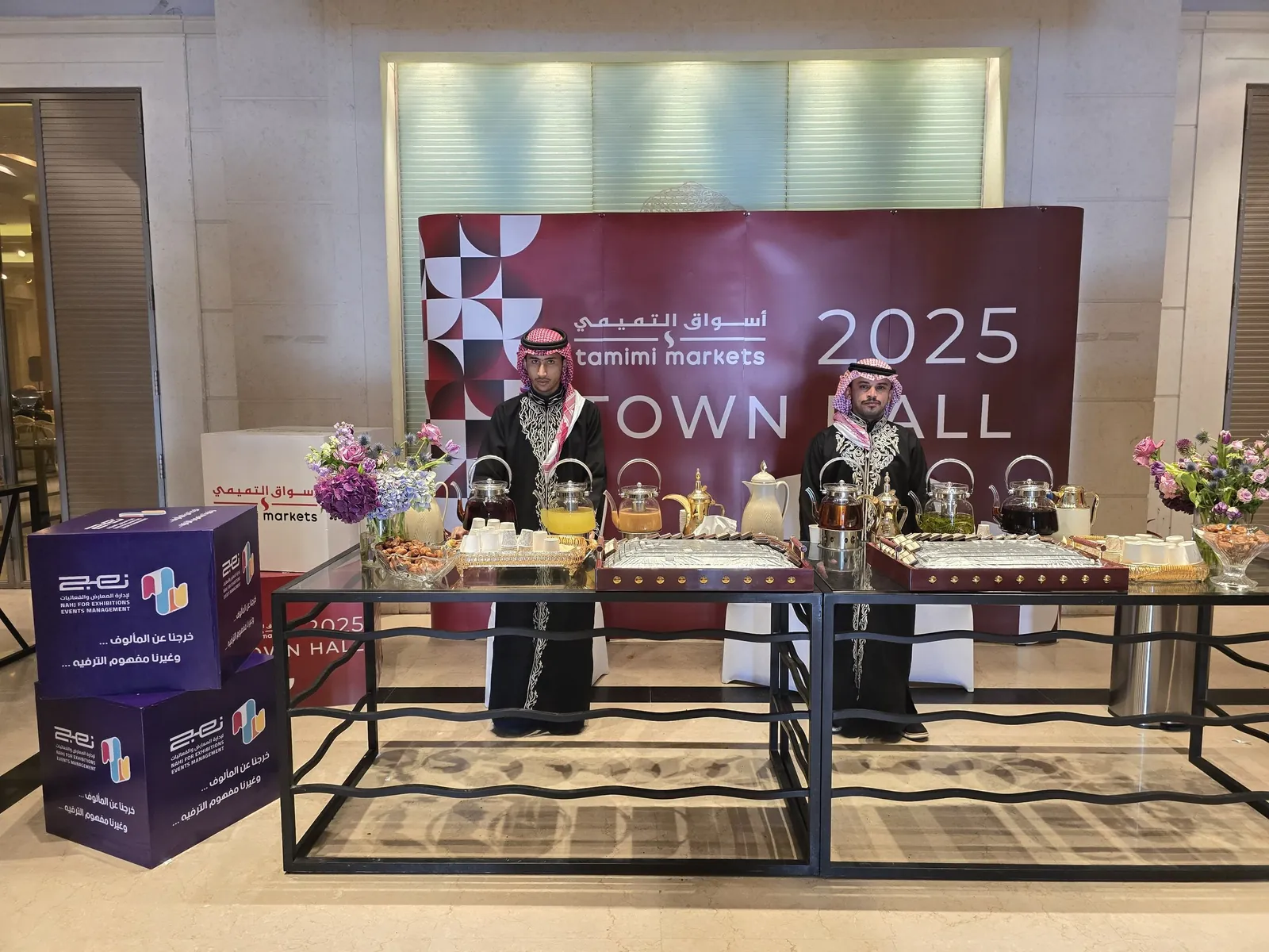 Coffee & tea station with traditional-dress hosts before branded Town Hall backdrop