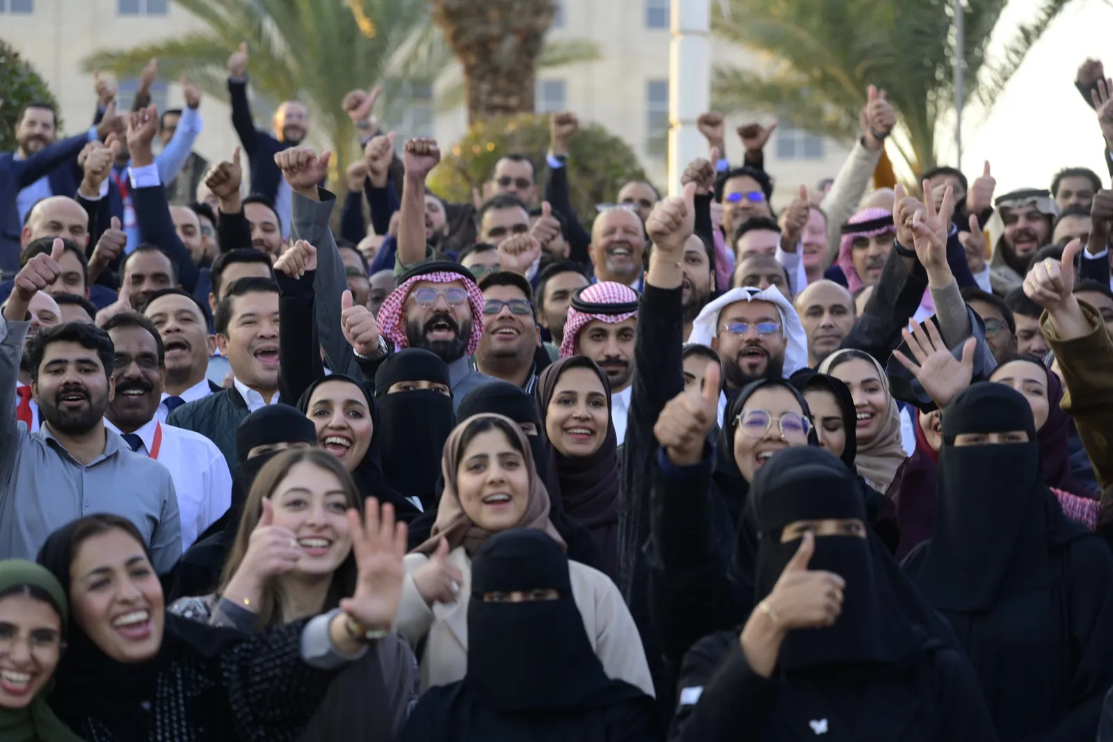 Employees cheering with thumbs up and raised fists in group photo