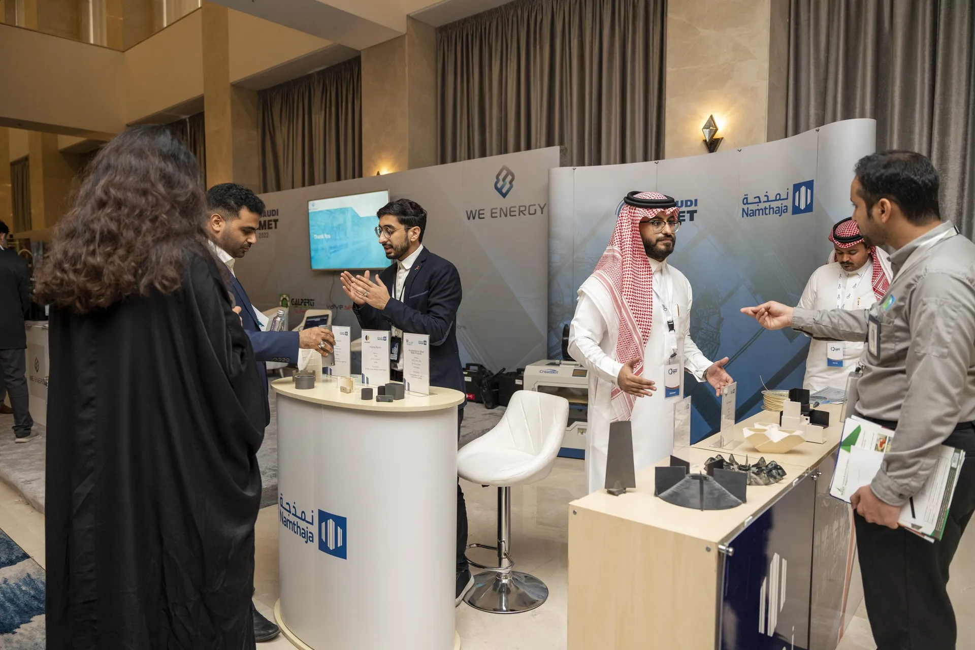 Exhibitors demonstrating 3D-printed parts to visitors at Namthaja booth