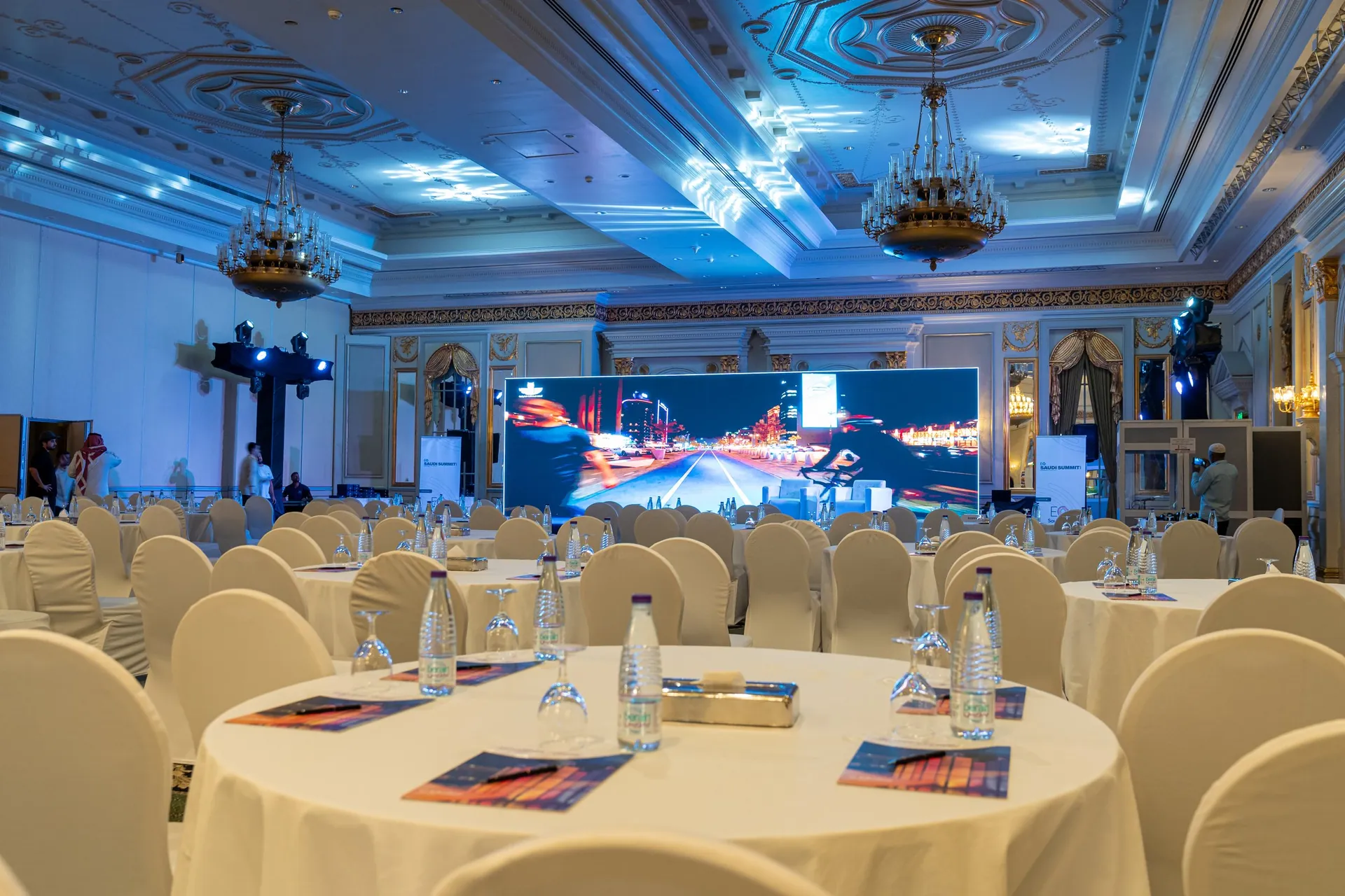 Dressed rounds in foreground, LED stage and blue-lit chandeliers