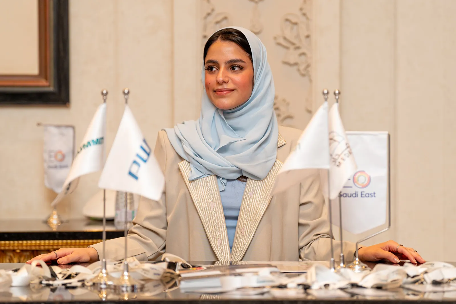 Smiling hostess at registration desk with sponsor flags