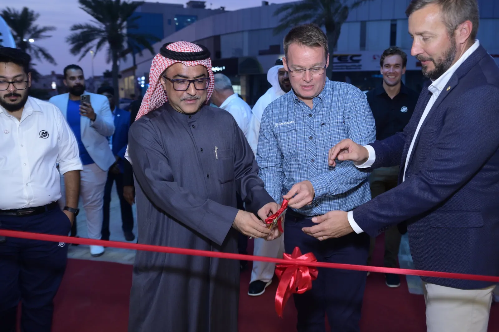Ribbon cutting moment with guests behind at dusk